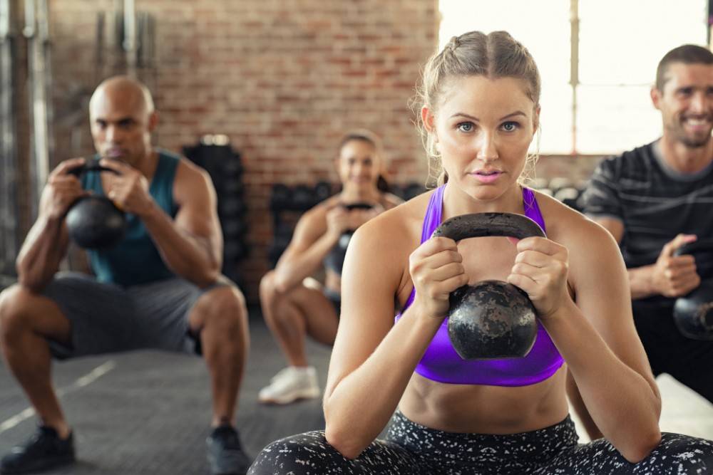 Group fitness class squatting with kettlebells