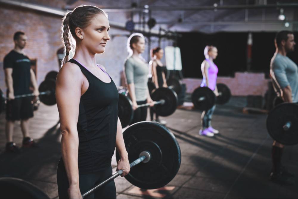 Members setting up for controlled barbell deadlifts