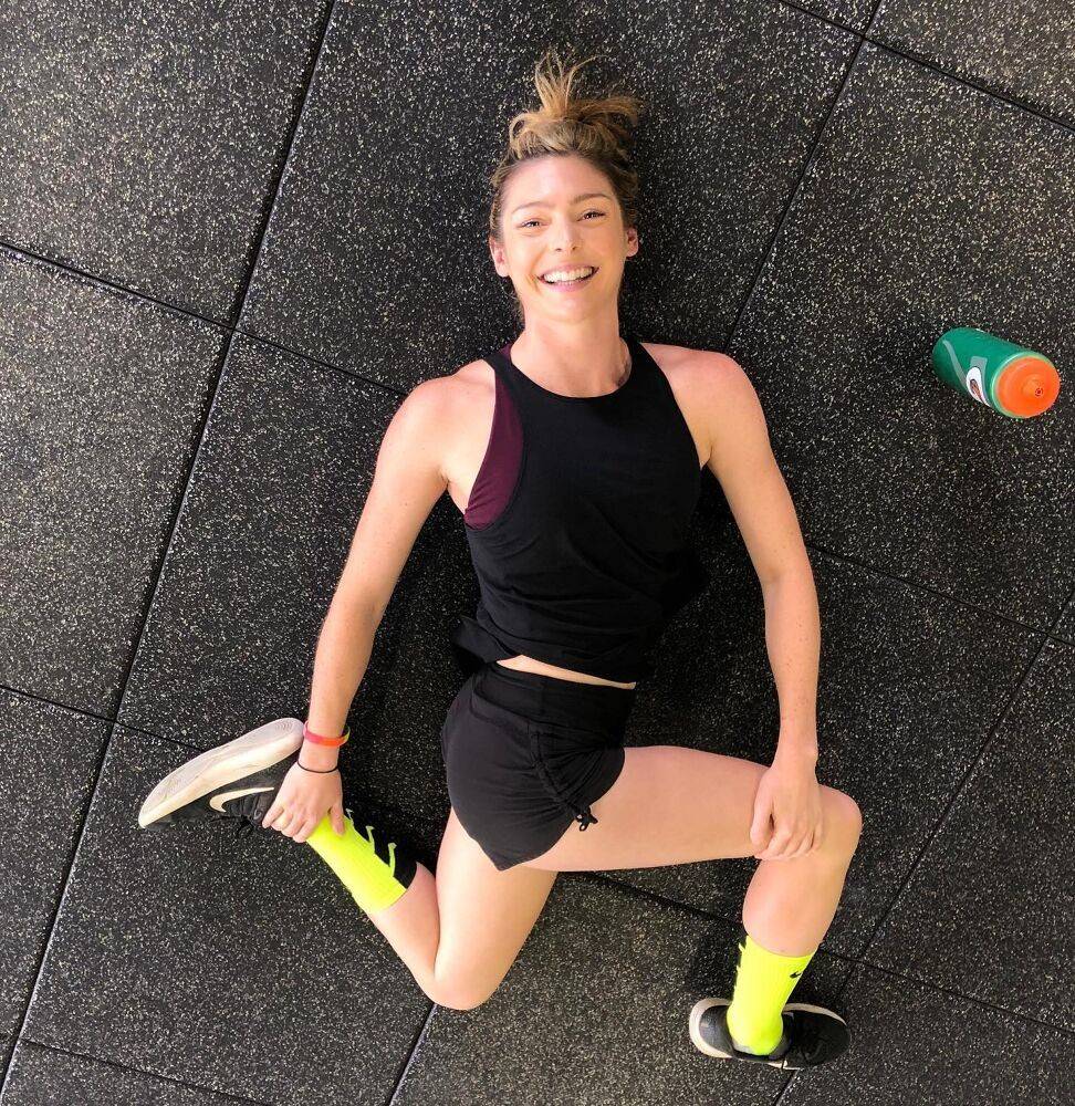 Member smiling through a floor stretch after class